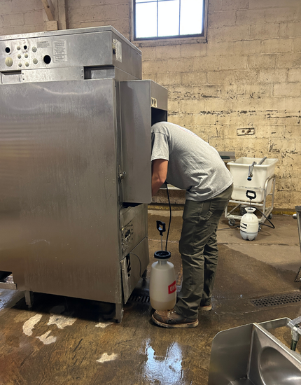 A large hood for a Commercial kitchen  covered in clear plastic sheeting for protection during maintenance in a commercial kitchen facility with exposed ceiling