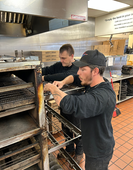 two pridecas technicians perform preventative maintenance on a commercial grade conveyor oven
