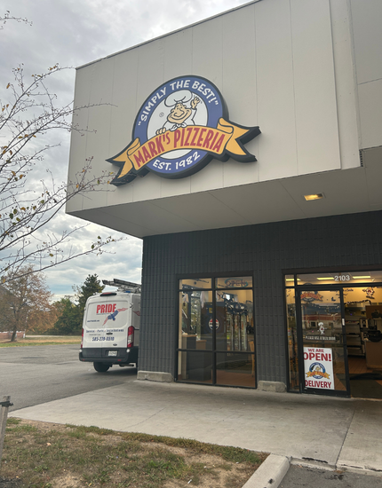 Entrance to a marks pizza store with a PrideCAS van parked outside