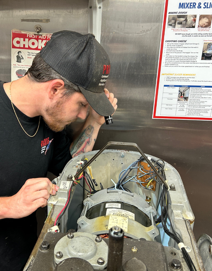 technician inspects a mixer with its electrical components in the top exposed