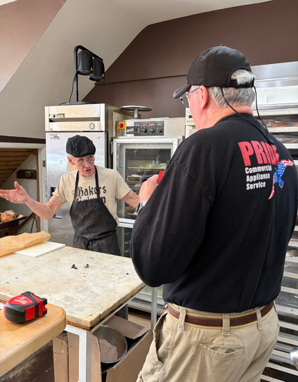pridecas worker speaking with bakery owner inside of bakery