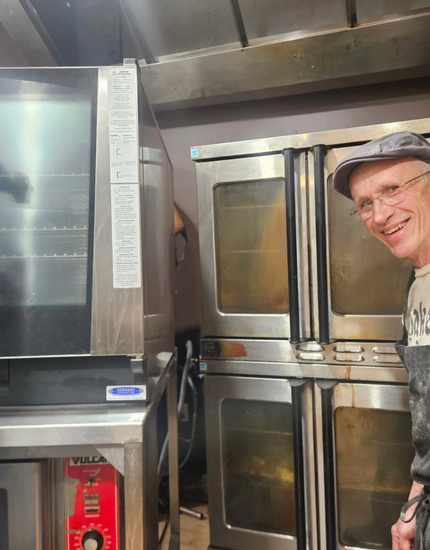 owner standing in front of new oven install and old oven being taken out