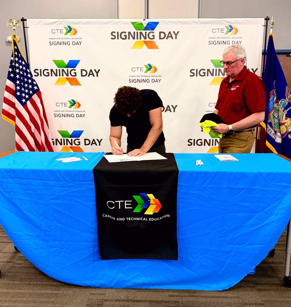 trever signing his letter of intent to join pridecas as a technician at his BOCES ceremony.